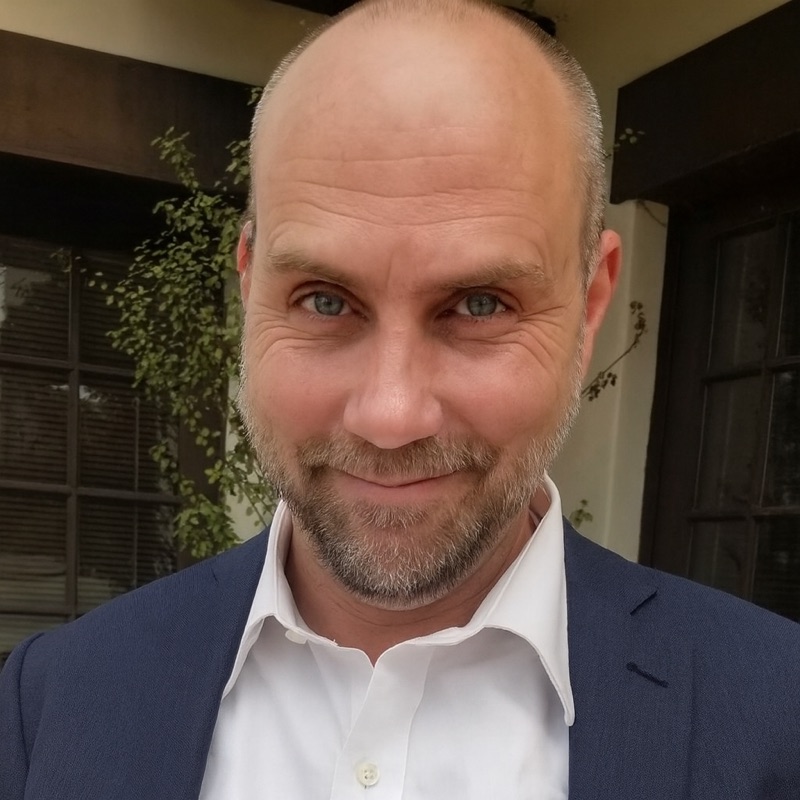 Stephen DeBaun, smiling, in a navy blazer and a white shirt.